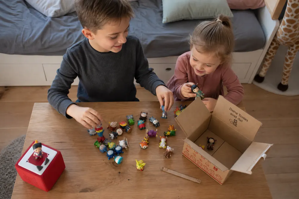 Kinder breiten ihre Tonie-Sammlung zum Sortieren auf dem Tisch aus